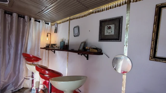 Framed artwork, a narrow shelf, and red and cream stools.